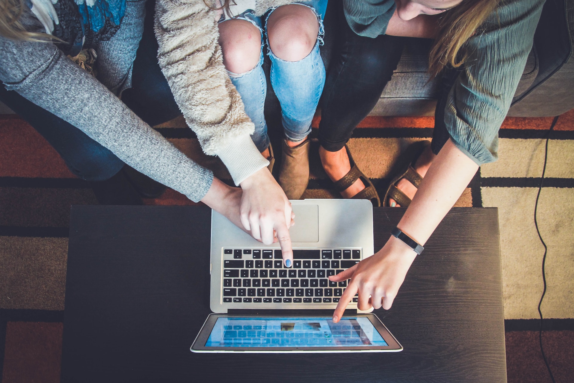 Three people pointing at a laptop screen.