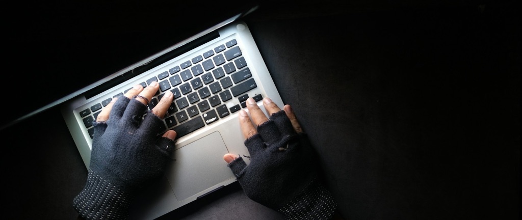Photo of hands in gloves on the keyboard of a laptop.